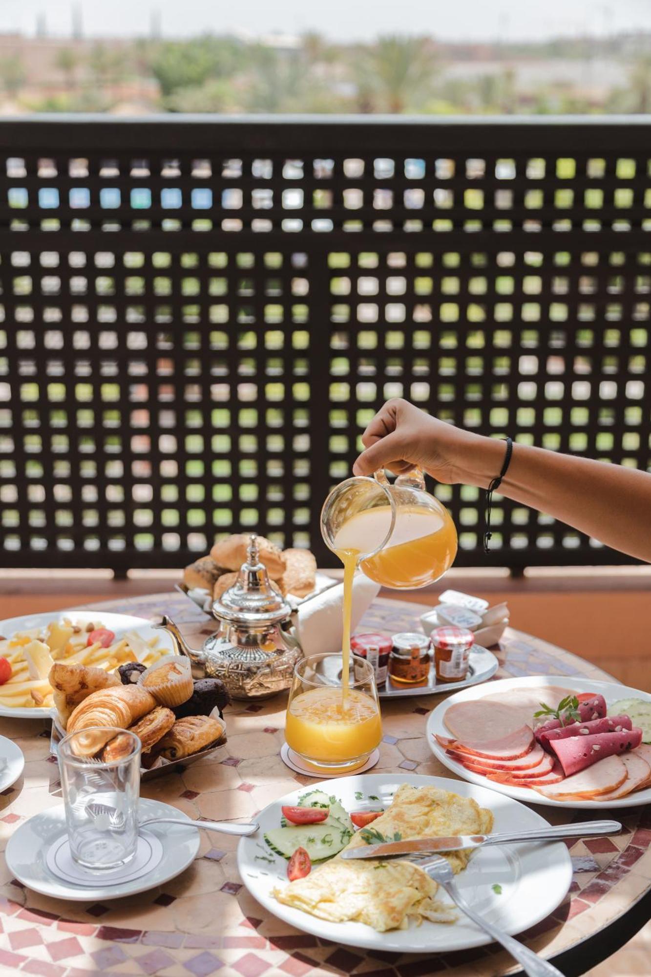 Kenzi Menara Palace & Resort Marrakesh Bagian luar foto A hand pouring a glass of orange juice
